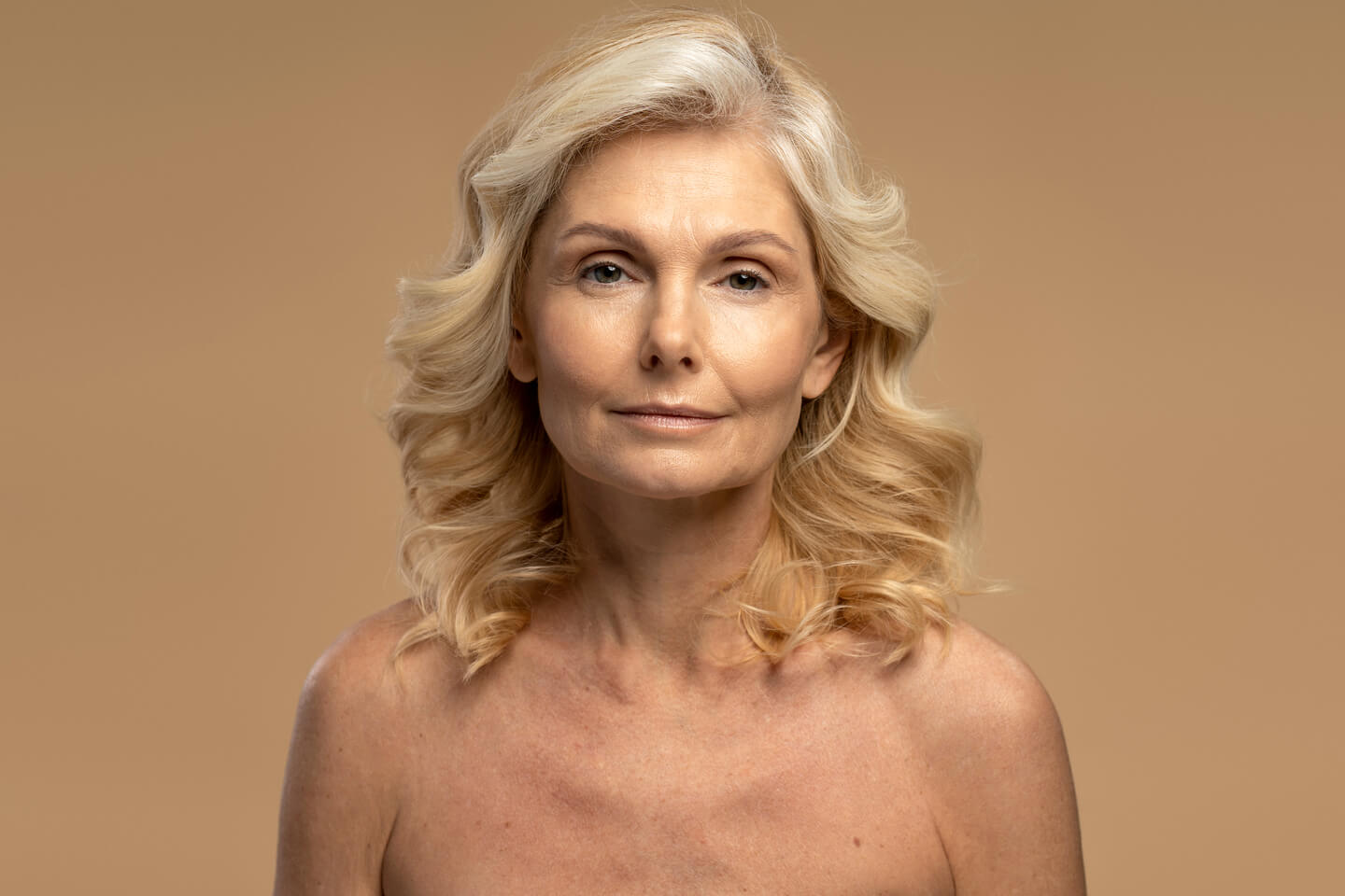 Beautiful Caucasian mature woman looking at camera isolated on beige background