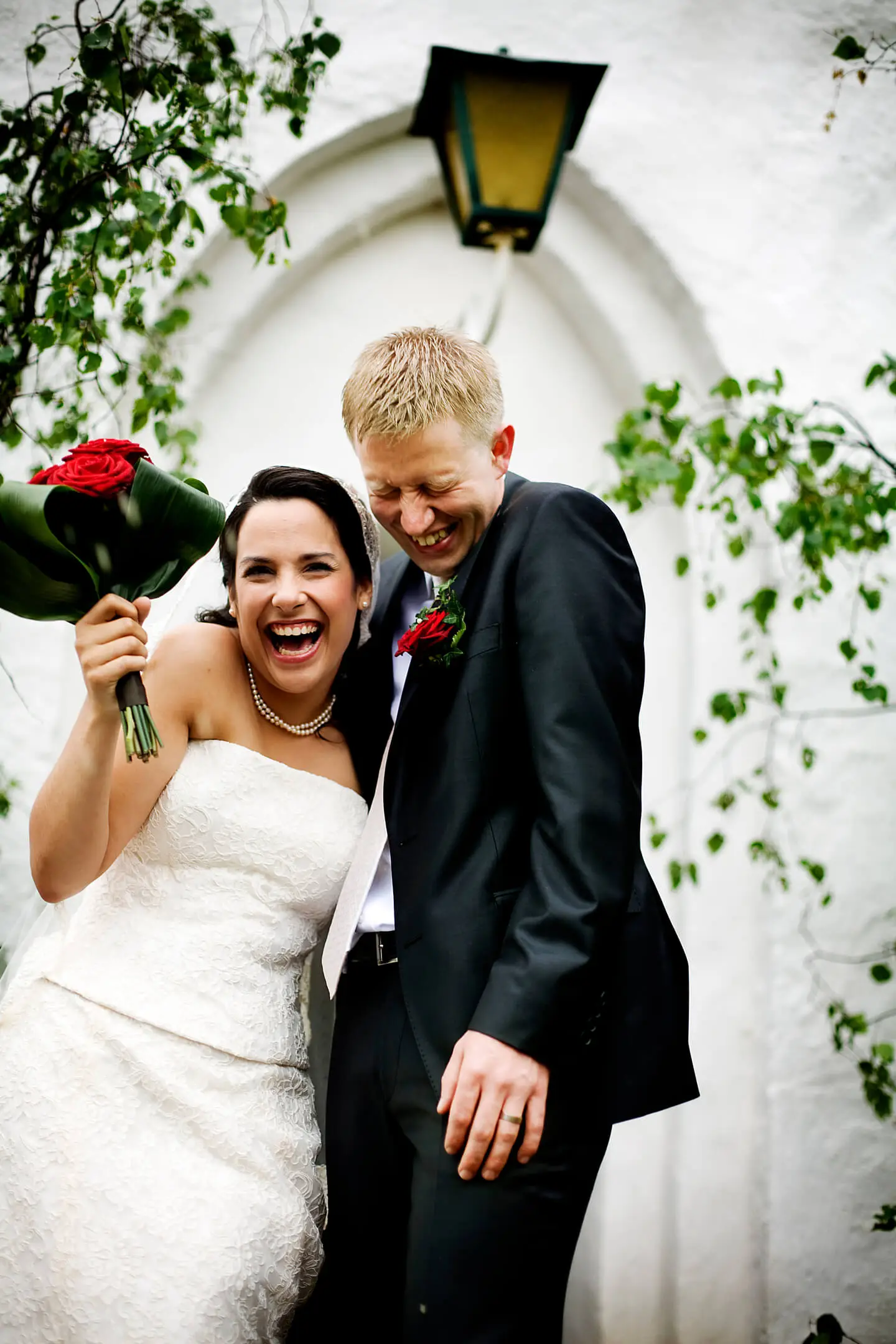 Cheerful bridegroom standing against building