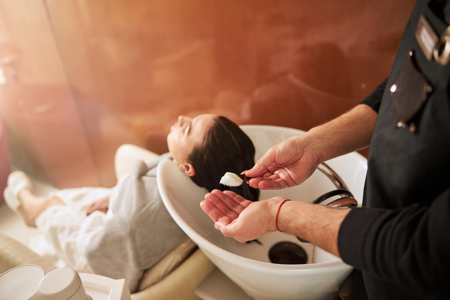 Hairdresser with a hairstyling product standing behind the client