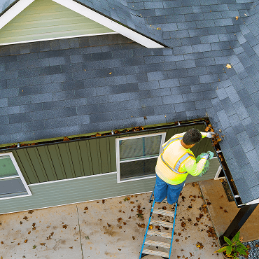 a worker is cleaning clogs in roof gutter drain
