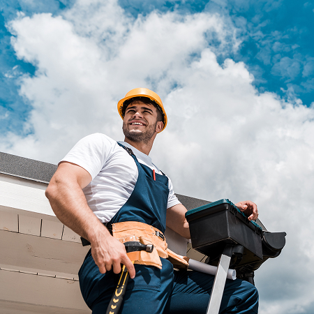 low angle view of happy repairman in helmet holding toolbox