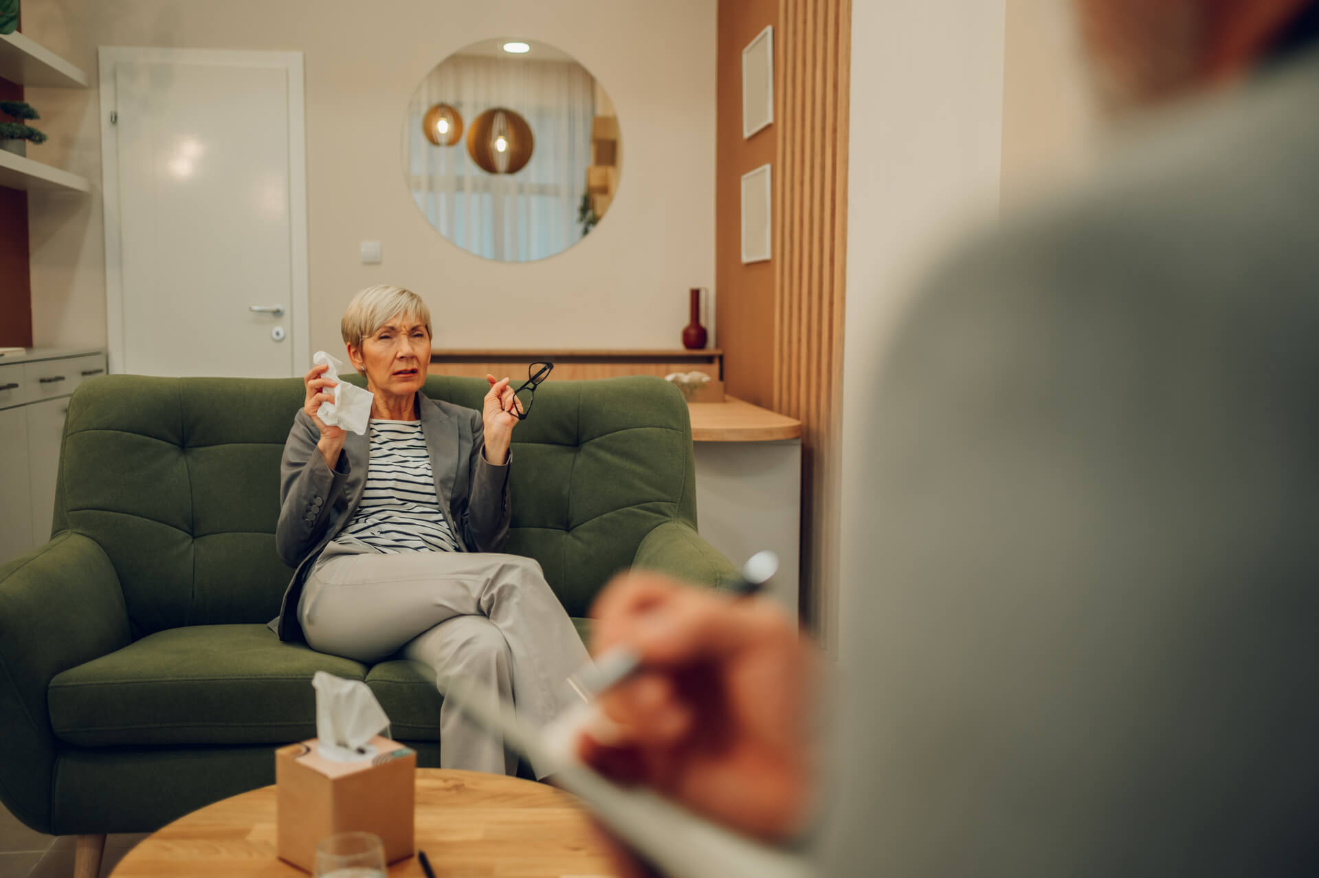 A senior female patient is having a session with a psychotherapist in a doctor's office