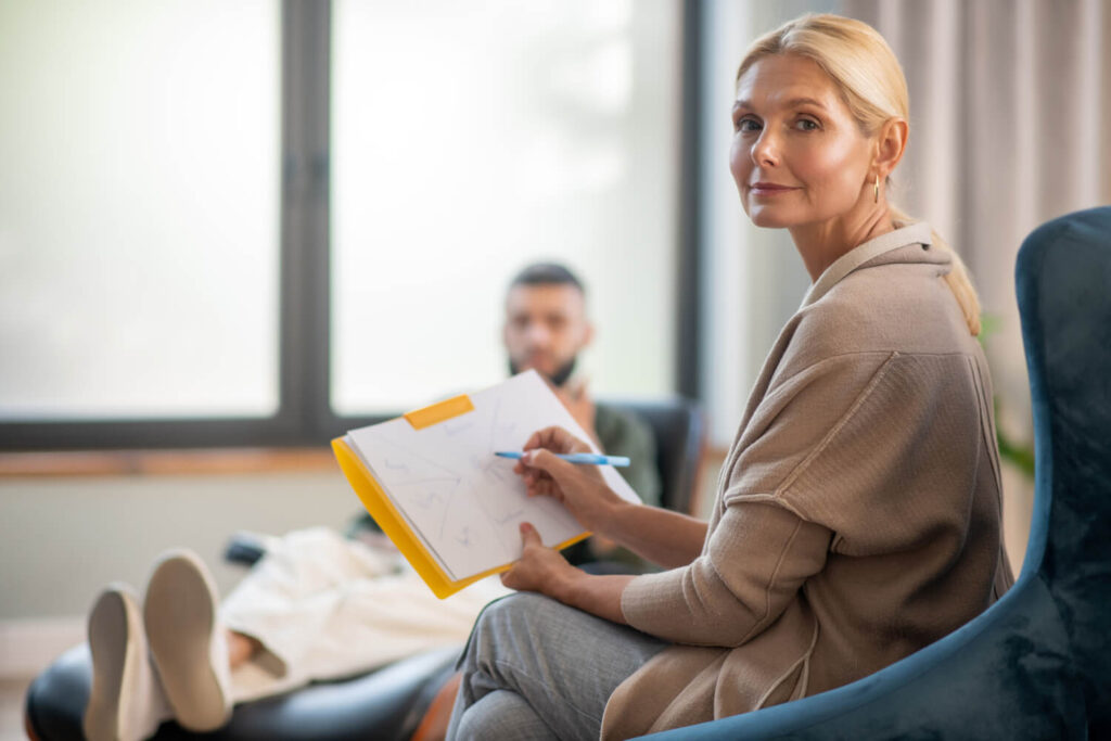 Woman Writes Notes While Man Relaxes on Couch